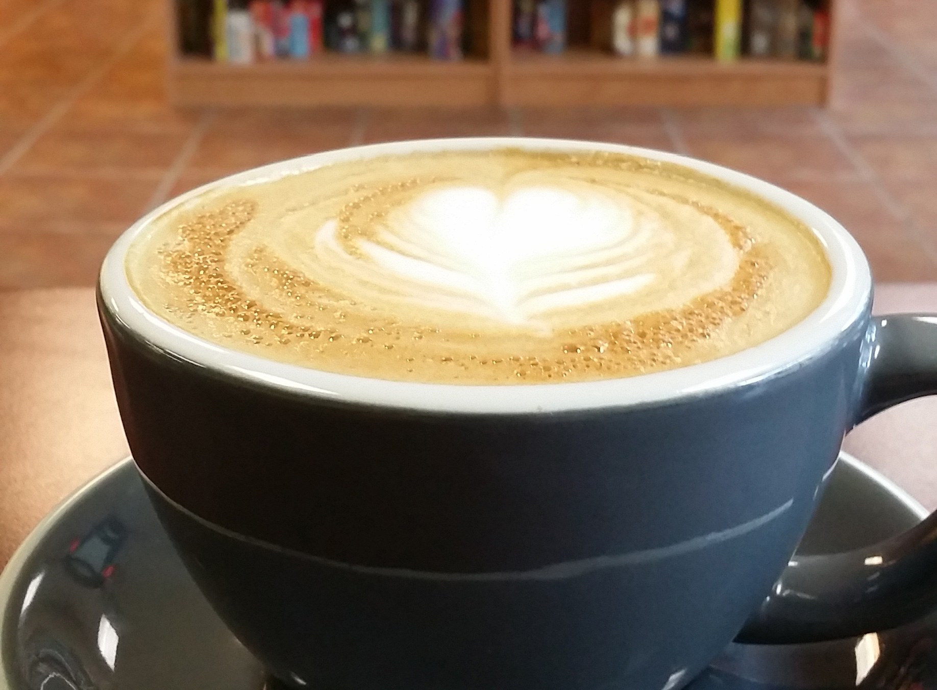 Latte art at The Cardboard Café with game shelves in the background
